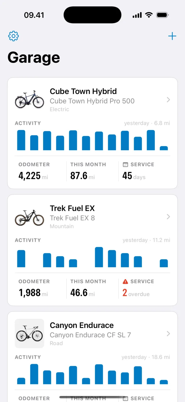 The Garage screen listing three bikes, each with a twelve-week activity chart and its odometer, distance this month and next service